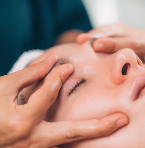 Cosmetologist using jade stone roller for Guasha face drainage massage